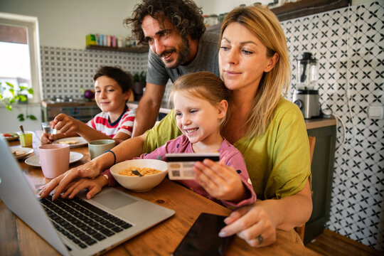 Parents and children shopping online in home kitchen