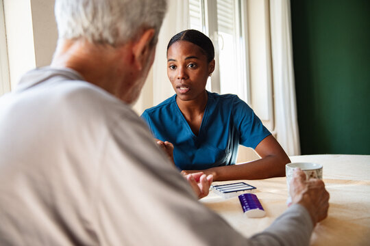 Nurse discussing medication with senior man at home