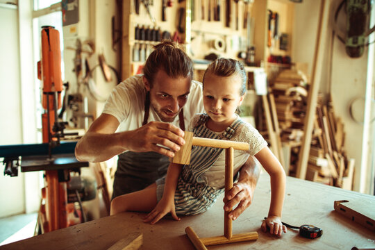 Father teaching daughter woodworking in home workshop