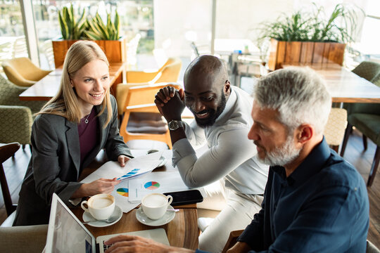 Diverse business team meeting with charts in a cafe