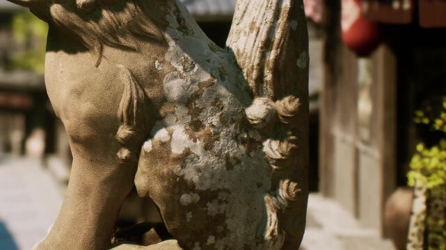 A weathered stone sculpture of a mythical creature stands in a serene village street, surrounded by rustic buildings and soft morning light, evoking a sense of history and mystery.
