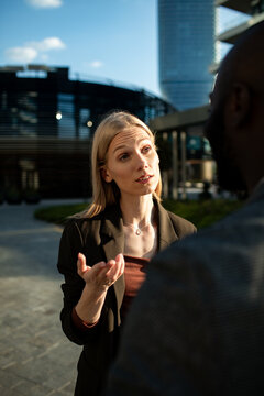 Businesswoman talking with colleague outdoors in city