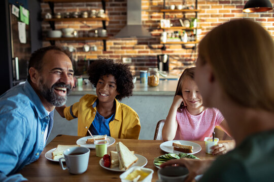 Parents and children enjoying breakfast in home kitchen