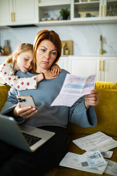 Stressed mother reviewing household bills at home with daughter