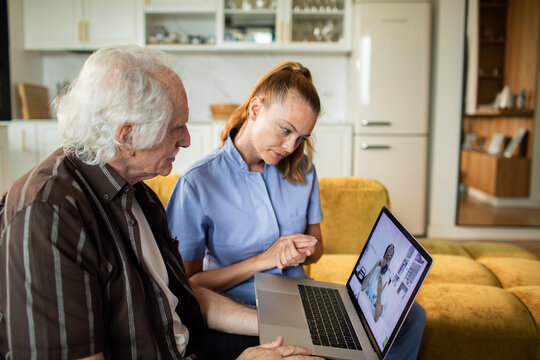 Caregiver assisting senior with telehealth video consultation at home