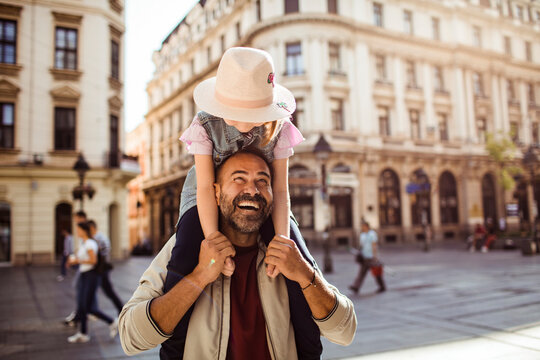 Father carrying daughter on shoulders in historic city street