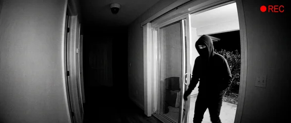 Surveillance Camera Captures Burglar in Hood and Balaclava Entering Home Through Sliding Door at Night © Kristelinmind