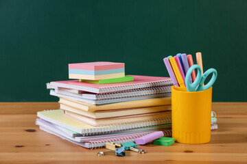 Different stationery on wooden table near chalkboard, closeup © New Africa