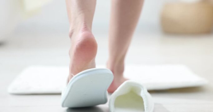 Woman taking off slippers and stepping onto soft bath mat indoors, closeup