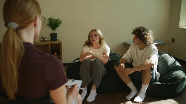A woman stands up and leaves the therapy session, while her partner remains seated with the psychologist, showing discord and emotional distance.