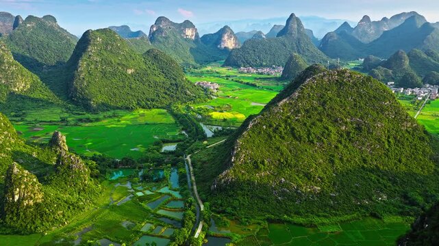 Aerial drone view of karst mountain peaks and green rice paddies in Guilin, Guangxi, China.