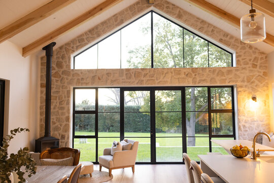 Central glass doors are opening to green lawn, black-framed wall framing armchair and stove