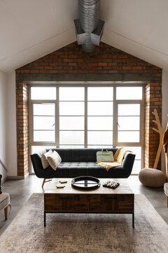 Tufted dark sofa is anchoring loft living room with mustard throw, pale green tote, coffee table