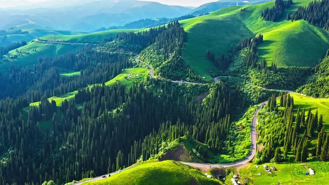 Aerial view of mountain pass road winding through green alpine meadows on Duku Highway, Xinjiang, China.