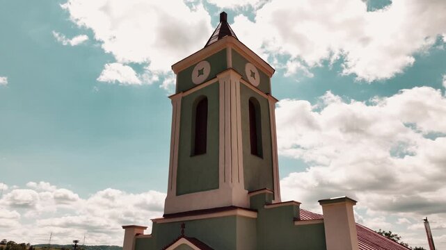 Historic Rural Church with Clock Tower and Wind Turbine Under Blue Sky