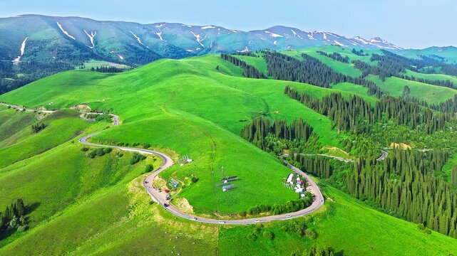 Aerial view of serpentine road winding through lush green mountains on Duku Highway, Xinjiang, China.