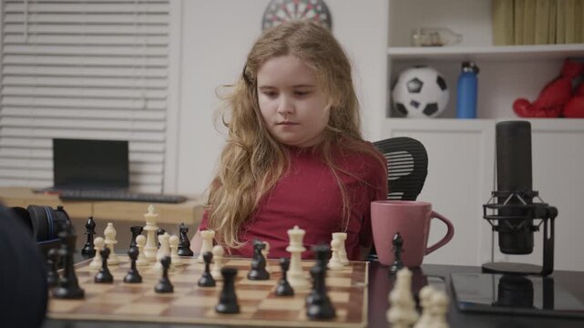 Kid analyzing chess position at home. Child studying chess patterns carefully. Kid moving chess pieces with focus. Child learning logic through chess play. Kid practicing strategy with a chessboard.