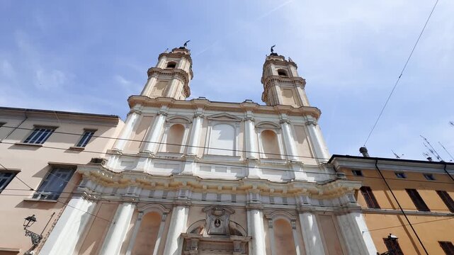 Low-angle view of the former San Francesco di Paola church in Parma, Italy, highlighting its symmetrical Baroque facade, twin bell towers and ornate architectural details.