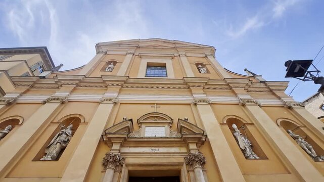 Low-angle view of Chiesa di San Vitale in Parma, Italy, showing its warm Baroque facade, saint statues, classical pilasters and ornate historic entrance.