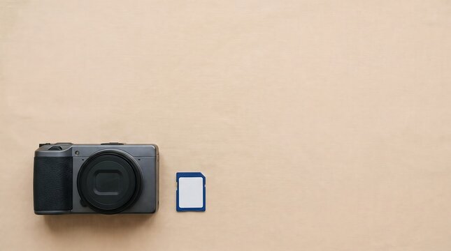 A digital camera and a memory card placed neatly on a light brown background surface, top view