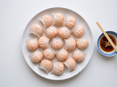 Steamed shrimp dumplings arranged on a white ceramic plate with dipping sauce