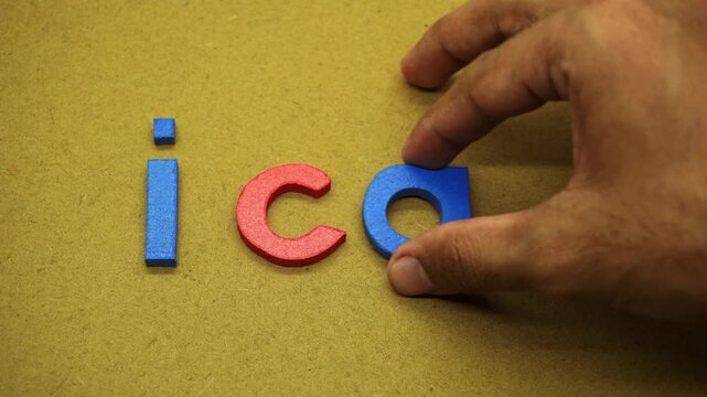 A person arranges colorful wooden alphabet letters to spell the motivational phrase I can on a textured cardboard background, symbolizing positivity, determination, and confidence.