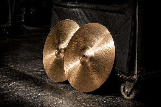 Polished orchestral cymbals leaning against padded cart backstage, music equipment and performance preparation concept