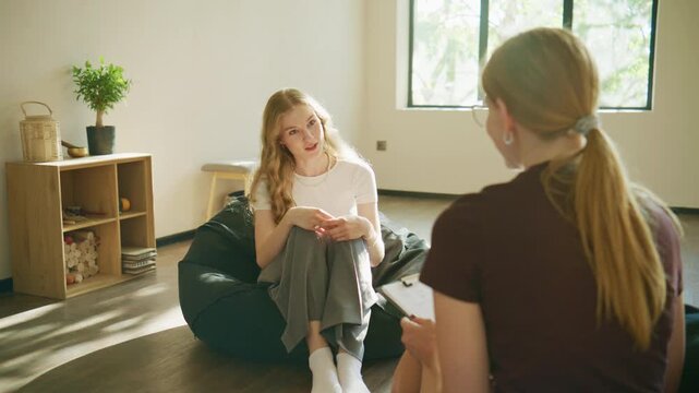 Psychology session in a bright room with a woman sitting on a beanbag chair talking to another person