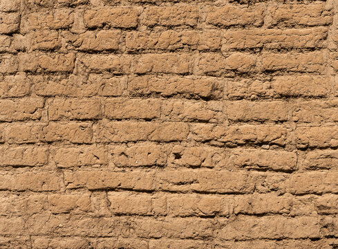 Old adobe brick wall texture with natural earthen surface and rustic brown tones for architectural backgrounds and design