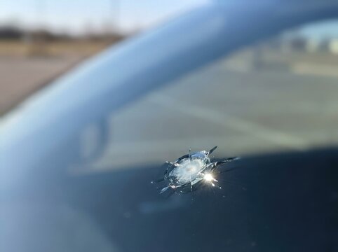 Small chipped stone impact on vehicle glass forming a tiny...