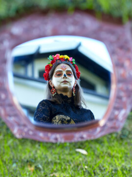 Halloween portrait of woman with in a mirror. Face and a house are reflected in the mirror.