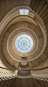 Spiral staircase with stone steps metal railings and skylight symmetry creating geometric precision