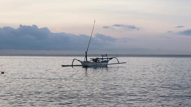 Traditional Indonesian Jukung Outrigger Fishing Boat Floating on Calm Sea at Dawn in Teluk Waru