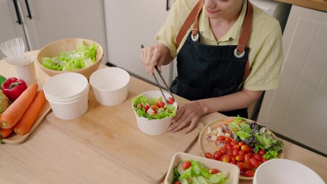 Close up of woman preparing multiple salad bowls for small food business. 