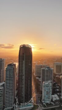 Surfers Paradise at dusk from above, warm light across the skyline and beach, Gold Coast, Queensland Australia - vertical video
