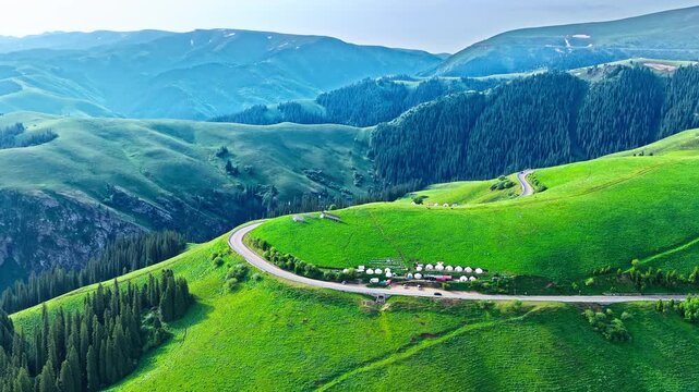 Aerial view of serpentine road winding through lush green mountains on Duku Highway, Xinjiang, China.