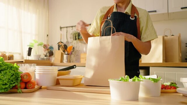 Close up of a woman preparing multiple salad bowls for small food business. 