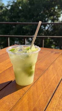 Rio de Janeiro, Brazil A Woman's Hand Grabs a Caipirinha, Famous Tropical Drink Out of Frame on Picnic Table. Lime, Paper Straw - Vertical Video