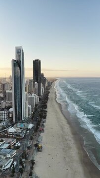 Surfers Paradise at dusk from above, warm light across the skyline and beach, Gold Coast, Queensland Australia - vertical video