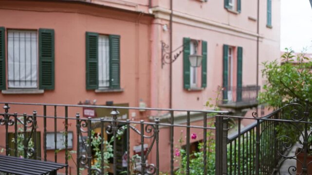 Balcony railing and terracotta building facade in soft blurred bokeh with shallow depth of field street; background backplate copyspace calm.