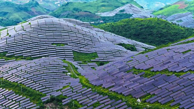 Aerial view of a large-scale solar farm on green mountain slopes for renewable energy in Guizhou, China