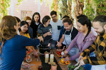 Obraz premium Group of Latin American Adult Students With Teacher Preparing recipe ingredients in Cookery Class in Mexico. Hispanic people multi generations learning together to cook in a terrace outdoors