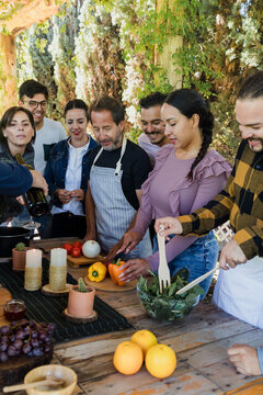 Group of Latin American Adult Students With Teacher Preparing recipe ingredients in Cookery Class in Mexico. Hispanic people multi generations learning together to cook in a terrace outdoors