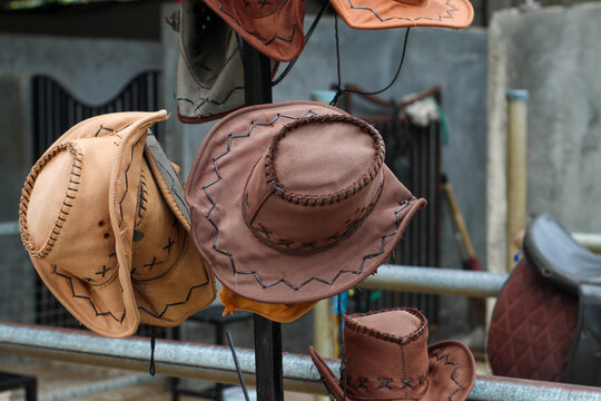 Several brown and cream cowboy hats hung neatly on a display rack in the outdoor area.
