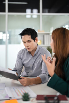 Two professional businesspeople discussing documents , focused collaboration, reviewing financial reports during an office meeting