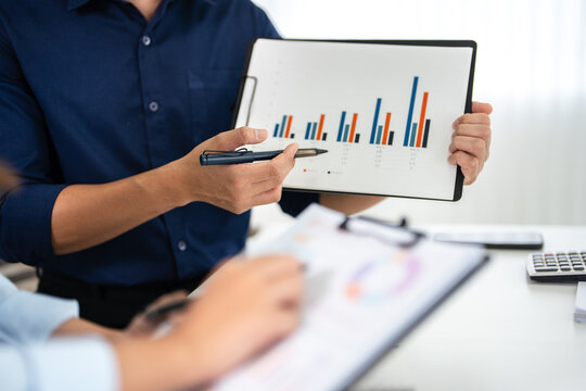 Close up hands of Two colleagues engaged in business analytics, over financial charts. Colleagues Collaborating on Business Analytics