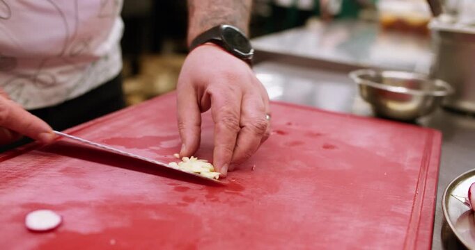 Chopping garlic. Spicy recipe. Male chef hand mincing by sharp knife on kitchen board clove ingredient for hot tasty healthy dish.