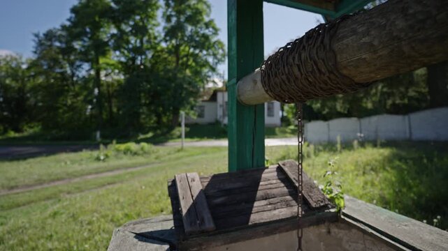 Wide angle of a pulley well system with an axel and a chain on it. The axel of the pulley well rotating back and forth. Ascending and descending well pulley chain.