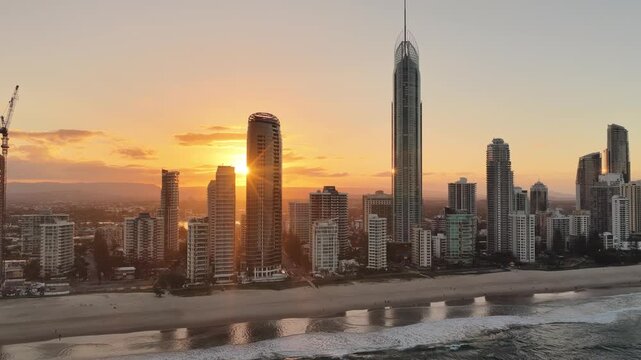 Surfers Paradise city skyline glowing at sunset above the beach, aerial drone view, Gold Coast, Queensland Australia
