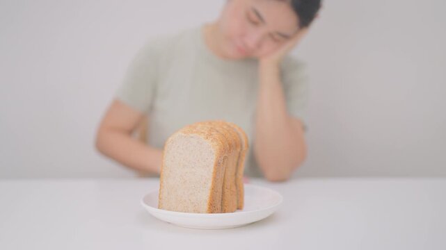 Unhappy woman disgust gesture and Bored to eat bread. concept of gluten intolerance, gluten sensitivity, carb loading concerns, or a disliking for unhealthy dietary habits